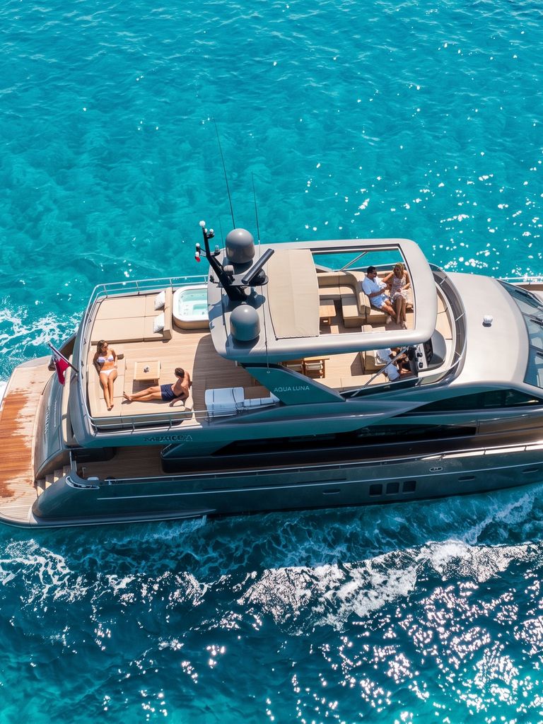Aerial view of a yacht leaving a wake across turquoise water