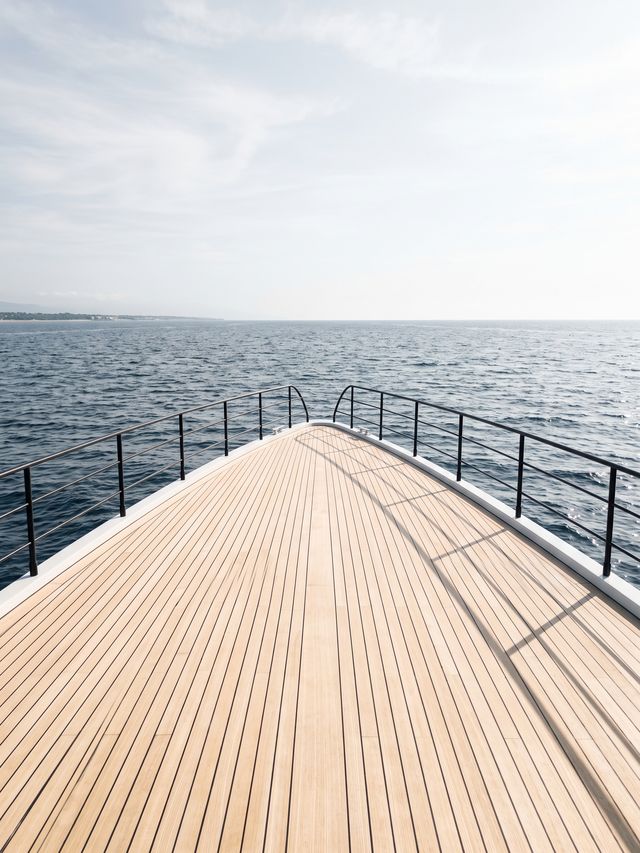 Teak bow deck of a yacht pointing to the open horizon